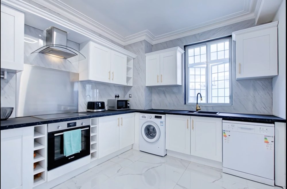 A galley kitchen in white and marble.