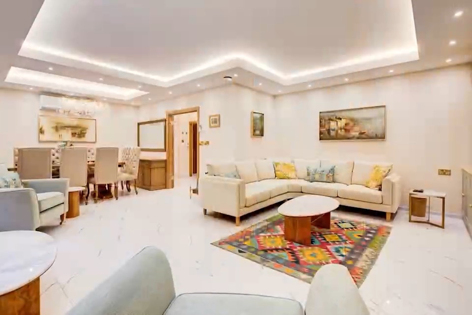 A long living room in cream and marble, a kilim rug in front of the sofas.